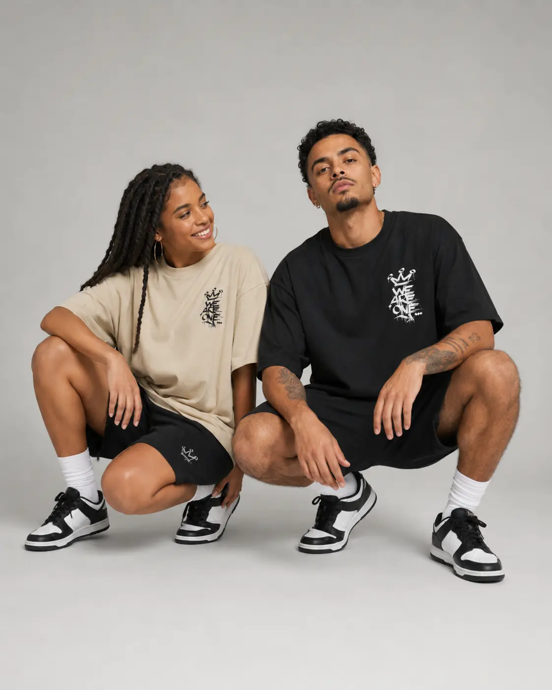 Deux modèles accroupis portant la collection streetwear WE ARE ONE